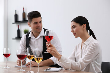 Sommeliers tasting different sorts of wine at table indoors