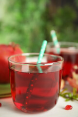 Pomegranate juice and fresh fruits on white table outdoors