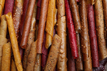 Delicious fruit leather rolls as background, top view