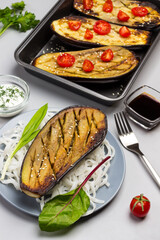 Baked eggplant with greens and rice noodles on plate.