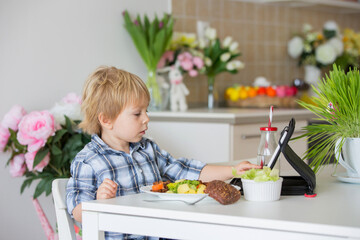 Little toddler child, blond boy, eating boiled vegetables, broccoli, potatoes and carrots with fried chicken meat at home