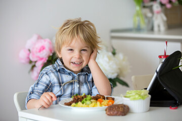 Little toddler child, blond boy, eating boiled vegetables, broccoli, potatoes and carrots with fried chicken meat at home