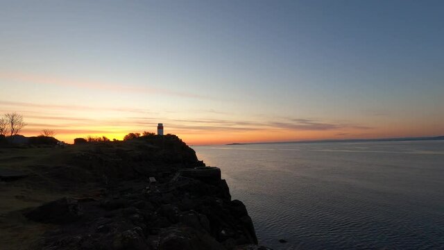 4k time lapse of sunrise over lighthouse at Aberdour, Fife, Scotland looking over the Firth of Forth estuary. Blue and orange sky, cloud movement.
