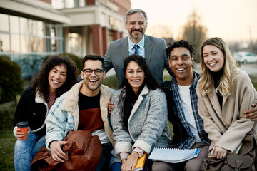 Portrait of happy mature professor with group of his students at campus.