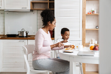 Black mother and son having breakfast together while sitting at home