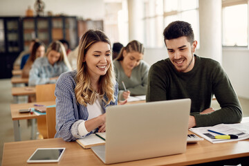 Happy university students using laptop while learning in the classroom.