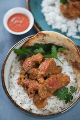 Close-up of a bowl with indian chicken butter masala, vertical shot on a grey concrete surface, selective focus