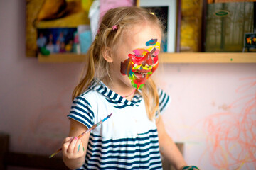 A happy child draws with colorful paints. Portrait of a child with a painted face. Happy childhood. selective focus
