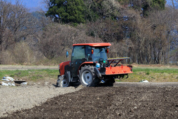 トラクターで田んぼを耕している男性　春　4月　田打ち