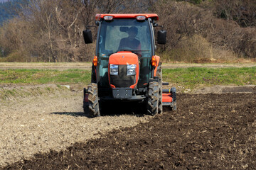 トラクターで田んぼを耕している男性　春　4月　田打ち