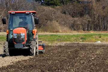 トラクターで田んぼを耕している男性　春　4月　田打ち