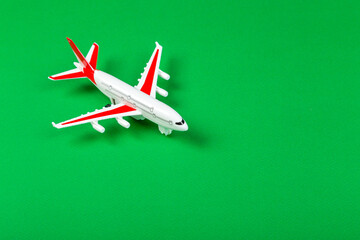 Fototapeta na wymiar plastic model of an airplane with red wings. tourism and travel concept. green background top view