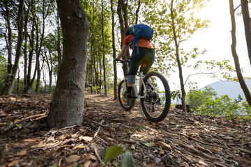 Fototapeta na wymiar Woman cyclist cycling on spring mountain top forest trail