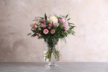 Beautiful bouquet with roses on table against grey background