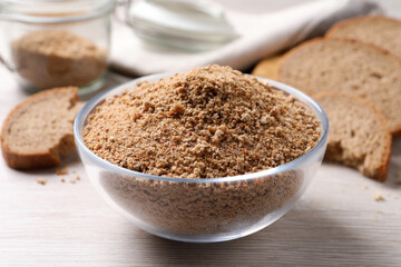 Fresh breadcrumbs in bowl on white wooden table