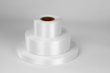 Top view tower of three coils of white satin ribbons of different sizes for labels or branding, isolated on a white, gray background.