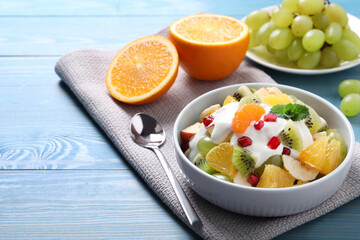 Delicious fruit salad on light blue wooden table, space for text