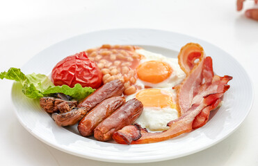 traditional English breakfast with sunny side up egg,toast,tomatoes,bacon,sausage and baked beans.
