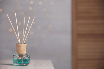 Aromatic reed air freshener on wooden table. Space for text