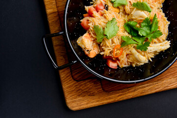 Seafood fried rice with green peas served in a wok pan over black background. Asian cuisine.
