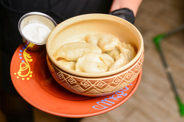 Closeup of traditional ukrainian food dumplings vareniky. Served on a ceramic plate by waiter in restaurant or diner.