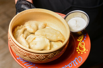 Closeup of traditional ukrainian food dumplings vareniky. Served on a ceramic plate by waiter in restaurant or diner.