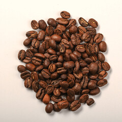 Pile of dark roasted coffee beans on white background