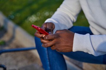 Close-up of black man's hands sending a message with a smart phone. Browsing social networks. Concept of technology
