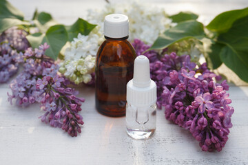 Obraz na płótnie Canvas Lilac, syringe essential oil (extract, infusion, tincture) with flower blossoms on white wooden background