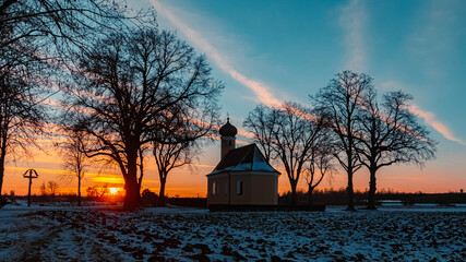Beautiful sunset with a church silhouette and dramatic clouds near Wallersdorf, Bavaria, Germany