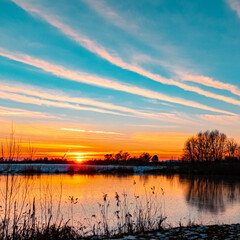 Beautiful sunset with reflections and dramatic clouds near Wallersdorf, Bavaria, Germany