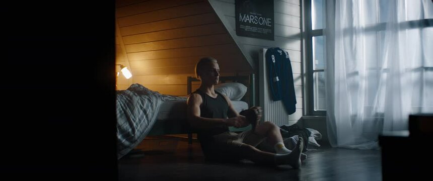 WIDE bored Caucasian teenager sitting in his bedroom, playing baseball catch with himself at home. Shot with 2x anamorphic lens