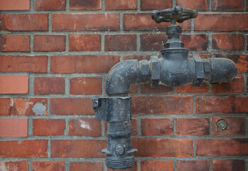 Dirty water faucets and pipes on the wall of an old brick building