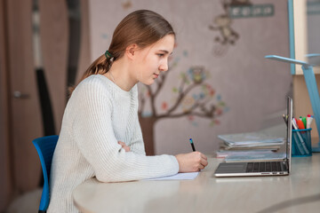 Beautiful schoolgirl studying at home doing school homework. Distance learning online education