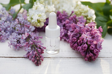 Lilac, syringe essential oil (extract, infusion, tincture) with flower blossoms on white wooden background