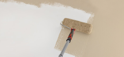 painting wall in mocha beige color with paint roller. banner copy space
