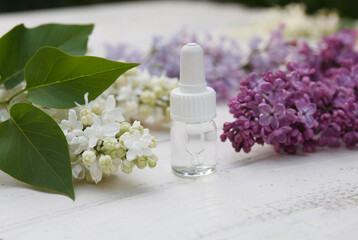Obraz na płótnie Canvas Lilac, syringe essential oil (extract, infusion, tincture) with flower blossoms on white wooden background