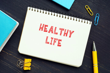 Business concept about HEALTHY LIFE with sign on the page. A healthy lifestyle is one which helps to keep and improve people's health and well-being.