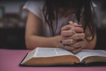 a woman is praying in front of the bible