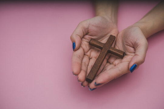 a wooden cross is held in the palm of hands
