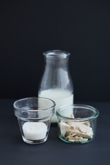 Dough starter ingredients in transparent glasses on dark background. Fresh wild yeast, milk and sugar as dough ingredients concept. High quality vertical photo
