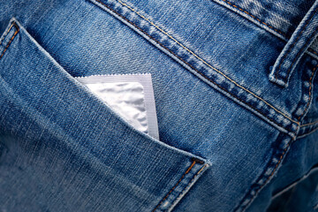 Close-up of a condom peeking out of the back pocket of blue jeans