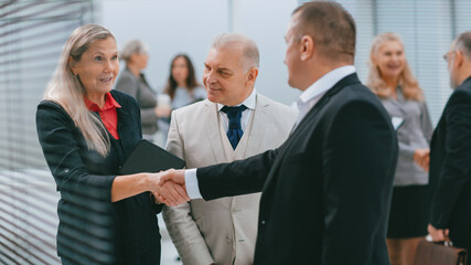 smiling businesswoman meeting colleagues with a handshake.