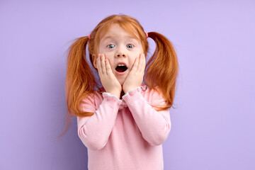 nice little surprised girl with ginger red hair and freckles, stands over purple background...
