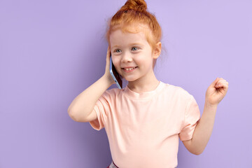 little redhead girl talking on phone indoors. concept of addiction of children and gadgets