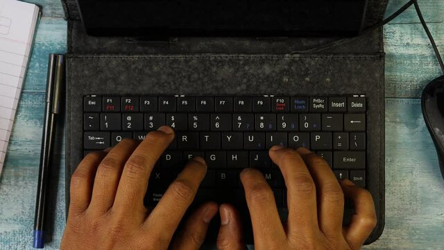 Top view of hands of an Indian man typing in keyboard of mini computer