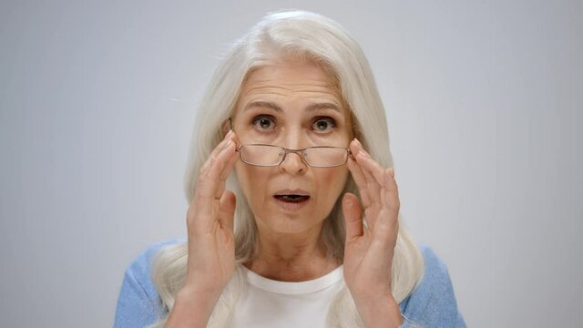 Stressed Senior Woman Looking Camera Indoors. Mature Lady Fixing Glasses Inside.