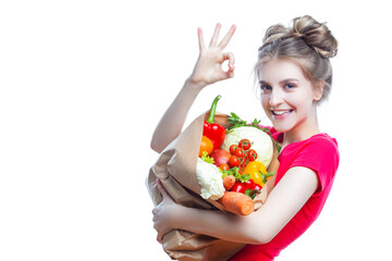 Young Caucasian Female Holding Eco Paper Bag Filled With Multiple Vegetables and Groceries Posing With OK Gesture Against White Background.