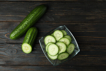 Bowl with ripe cucumbers on wooden background