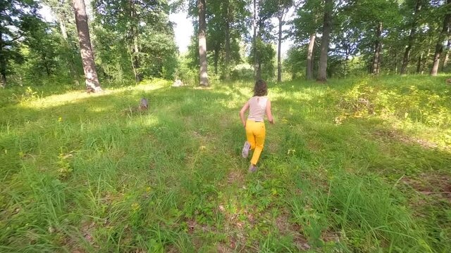 Teenage girl runs through summer oak forest. Russia